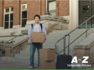 Student carrying boxes outside a college building, preparing for Moving to College