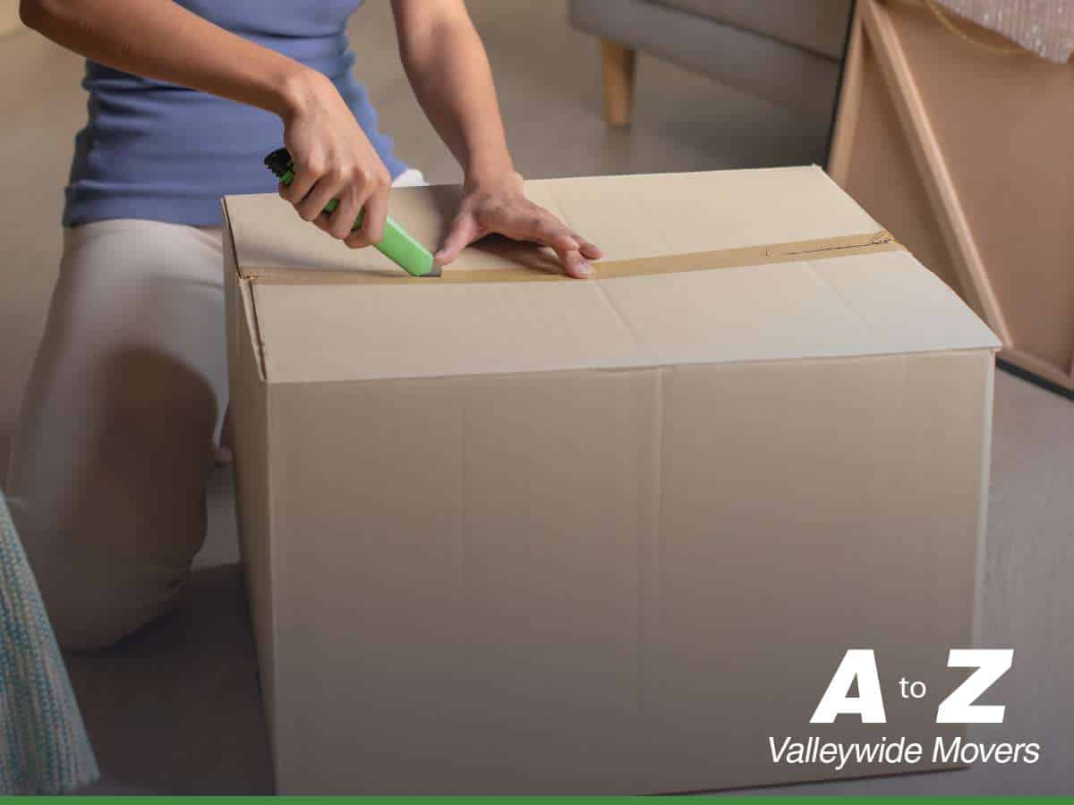 Person sealing a box with a cutter for a long-distance moving process